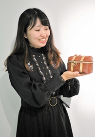魔法部で商品化したワンピース姿で、新作のポーチについて語る前田桃花さん＝神戸市中央区新港町、フェリシモ本社