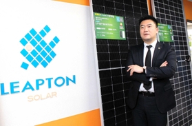 自社製造の太陽光パネルを背に展望を語る周鳴飛社長＝神戸市中央区相生町１、リープトンエナジー