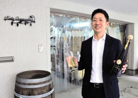 多彩な洋酒を収める倉庫を背に展望を語る大槻紘之社長＝西宮市青木町３、コートーコーポレーション