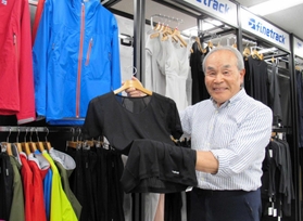 独自素材を使ったウエアを手に展望を語る金山洋太郎社長＝神戸市中央区相生町１