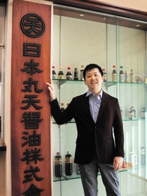古い自社の看板に手をかける９代目の延賀海輝社長。いつごろ作られたのかは不明という＝たつの市揖保川町半田