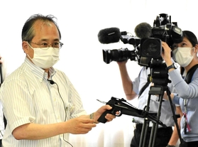 条例案の有識者検討会で実物のボーガンを手に説明する県の担当者＝７月、神戸市中央区
