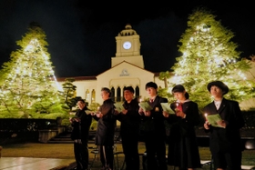 点灯したクリスマスツリーの前で、賛美歌を歌う学生ら＝西宮市上ケ原一番町、関西学院大西宮上ケ原キャンパス