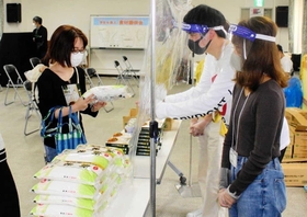 関西学院大学の寮生でつくる「繋がり隊」から食料を受け取った学生（左）＝関西学院大