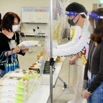 関西学院大学の寮生でつくる「繋がり隊」から食料を受け取った学生（左）＝関西学院大