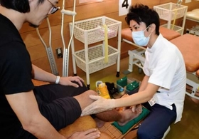 ふくらはぎなどの動きを患者（左）に意識してもらいながら、認知神経リハビリを行う理学療法士＝西宮市六湛寺町、県立西宮病院