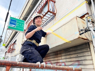 緑の看板のそばで制作する山田悠さん＝神戸市中央区元町高架通２