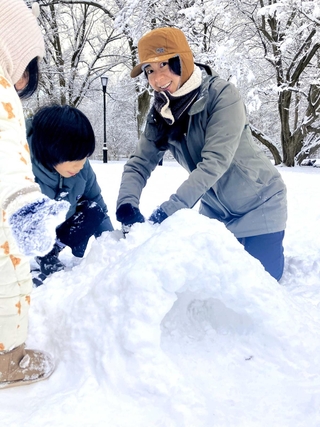たくさんの雪が積もる公園で、息子と娘とかまくら作り
