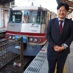 　富山地鉄１６０１０形の脇に立つ筆者。西嶋伸一さんが撮ってくださった＝２５年１０月２３日、富山市