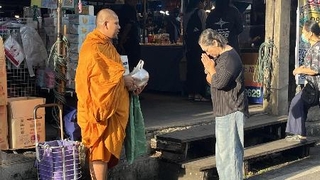　バンコクの朝市で、托鉢をする僧（左）と布施をする市民＝９月４日