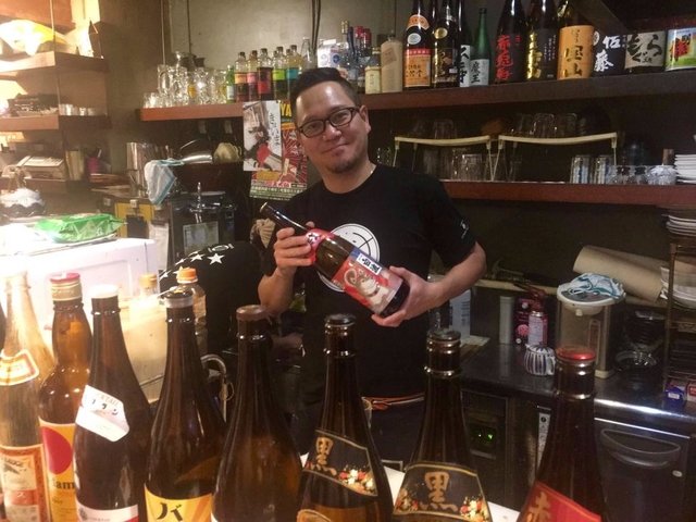 「西屋」のパルオ大将こと原口雅之氏。２０１８年の干支、戌（いぬ）のラベルがついた日本酒と