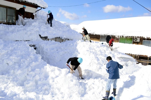 除雪の人手不足を受け、家屋に積もった雪を下ろすボランティアら＝２０１２年２月３日、新温泉町多子