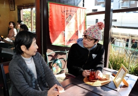 ベトナム紅茶を手に岩村さんと談笑する石だたみボーイズの高岩雄一さん（右）