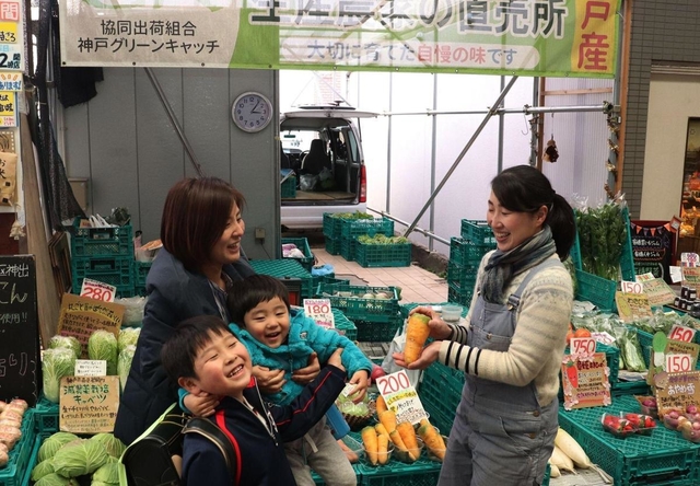 買い物客に野菜の特徴を説明しながら販売する西松由香里さん（左）＝東灘区甲南町３