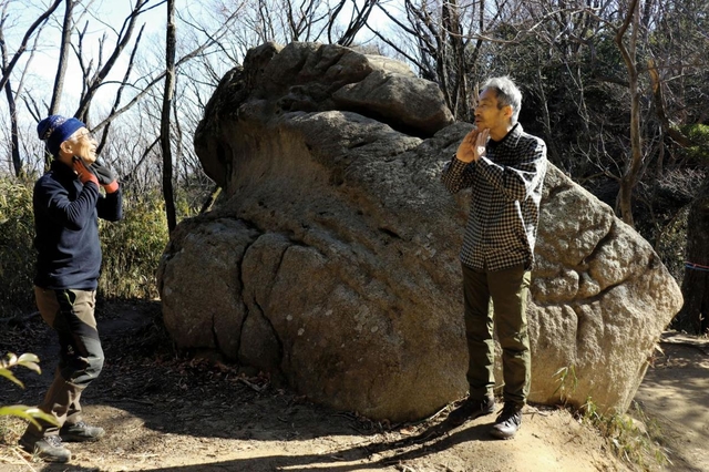 蛙岩。岩のくぼみを「カエルの首のよう」と話す森下孝一さん（左）と尾坂吉三郎さん＝神戸市東灘区内