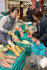 買い物客に野菜の特徴を説明しながら販売する西松由香里さん（左）＝東灘区甲南町３