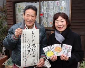 自宅の窓に絵手紙を飾る河野照夫さん（左）と絵手紙を描いた吉田光子さん＝東灘区甲南町３