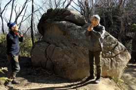 蛙岩。岩のくぼみを「カエルの首のよう」と話す森下孝一さん（左）と尾坂吉三郎さん＝神戸市東灘区内