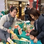 買い物客に野菜の特徴を説明しながら販売する西松由香里さん（左）＝東灘区甲南町３