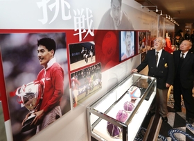 現役時代の雄姿など平尾誠二さんゆかりの品々が並ぶ展示コーナーに見入る式典出席者＝１０日午前、神戸市中央区港島中町６（撮影・大森　武）