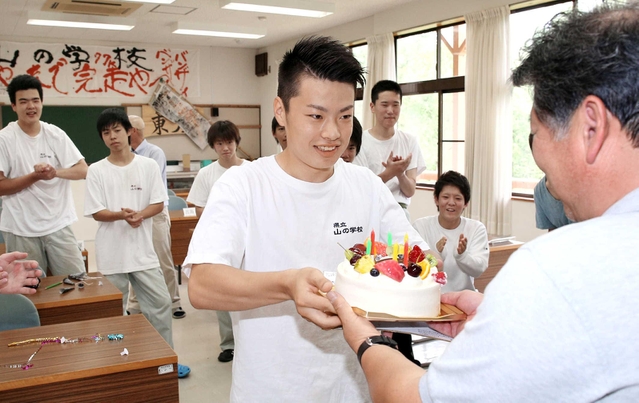 ７月９日。還暦の誕生日を迎えた中井さんにケーキを手渡す右田君＝宍粟市山崎町、県立山の学校（撮影・峰大二郎）