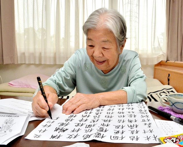 「木」が付く漢字を書く四元喜久子さん。部屋には塗り絵や計算ドリルも＝高砂市荒井町小松原１（撮影・後藤亮平）