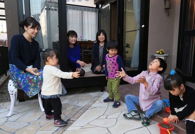 孫たちが遊ぶのをうれしそうに見つめる河本加津子さん（左から４人目）。にぎやかな夜が来る＝三田市つつじが丘北２（撮影・大森　武）