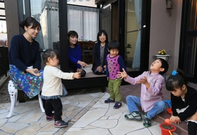 孫たちが遊ぶのをうれしそうに見つめる河本加津子さん（左から４人目）。にぎやかな夜が来る＝三田市つつじが丘北２（撮影・大森　武）