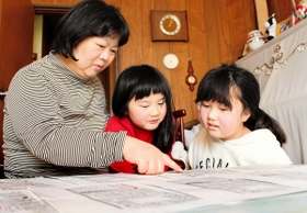 「このときのこと覚えてる？」。娘たちに過去の投稿記事を見ながら話す財田さん＝明石市