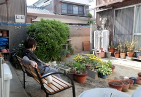 中庭のベンチに座る原とし子さん。何を考えているのだろう＝洲本市下加茂２、「ぬくもりの家　花・花」（撮影・辰巳直之）