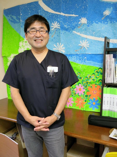 職員が作ったはり絵の前に立つ永井康徳医師。「医療は時代によって変わっていく」という＝松山市