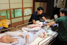 上田満さん、昌子さん夫妻の自宅を訪れ診療する花戸貴司医師（左）＝滋賀県東近江市