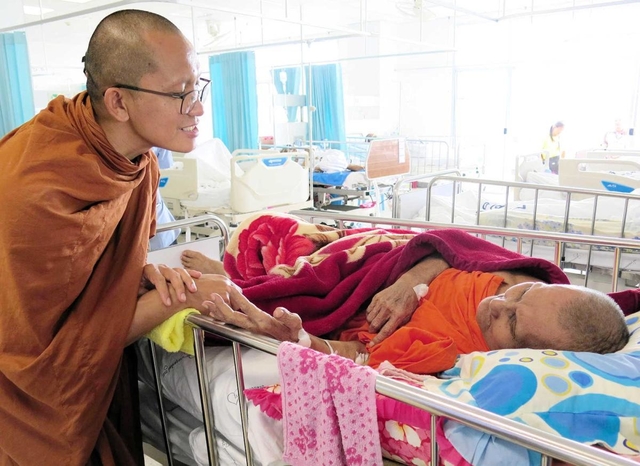患者に顔を寄せ、優しく話し掛けるスティサート師＝タイ北部・ウッタラディット県