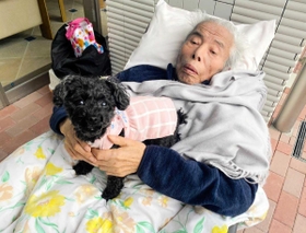 病院の敷地内でペットのトイプードルと触れ合う金森英彦さん（宮本亜紀子さん提供）