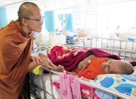 患者に顔を寄せ、優しく話し掛けるスティサート師＝タイ北部・ウッタラディット県
