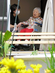 窓を開け、風を感じる「花・花」の入居者。庭には花が咲いていた＝洲本市下加茂２
