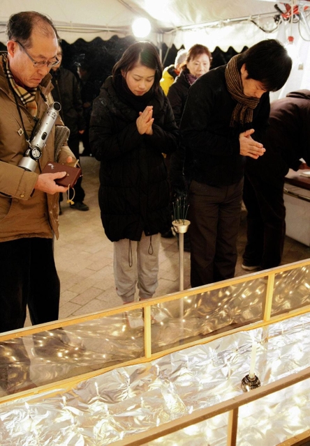 津知公園の追悼式典で献灯し、手を合わせる住民ら＝２０１３年１月１７日、芦屋市津知町