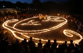 ろうそくの火を囲み、犠牲者に黙とうをささげる参加者＝１６日午後５時４６分、伊丹市昆陽池３、昆陽池公園（撮影・小林良多）