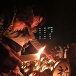 竹筒にろうそくの火を灯す人たち＝１７日早朝、神戸市中央区加納町６、東遊園地（撮影・冨居雅人）