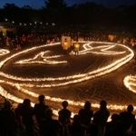 ろうそくの火を囲み、犠牲者に黙とうをささげる参加者＝１６日午後５時４６分、伊丹市昆陽池３、昆陽池公園（撮影・小林良多）