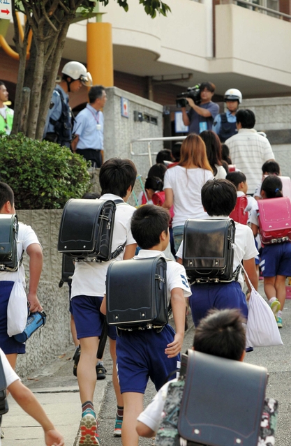 一斉に登校する児童ら。保護者が付き添う姿も見られた＝１６日午前８時７分、神戸市長田区房王寺町４、名倉小学校