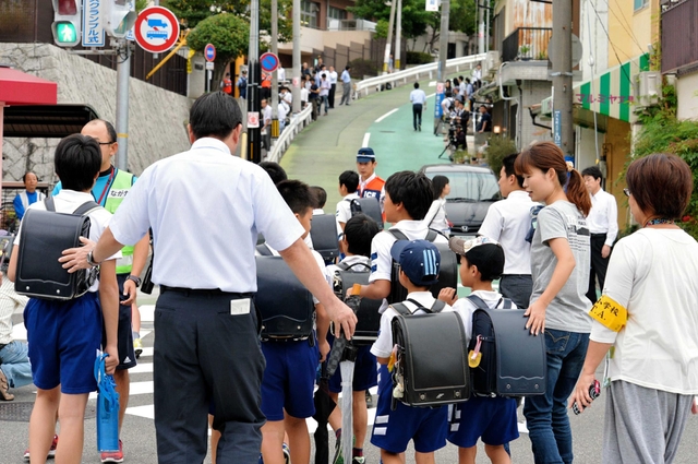 保護者や警察官に見守られ、登校する名倉小の児童＝２４日午前８時、神戸市長田区房王寺町４