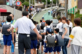 保護者や警察官に見守られ、登校する名倉小の児童＝２４日午前８時、神戸市長田区房王寺町４