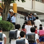 一斉に登校する児童ら。保護者が付き添う姿も見られた＝１６日午前８時７分、神戸市長田区房王寺町４、名倉小学校