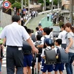保護者や警察官に見守られ、登校する名倉小の児童＝２４日午前８時、神戸市長田区房王寺町４