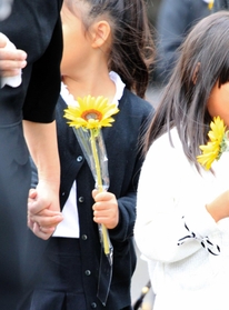葬儀の後、女児が好きだったというヒマワリを手に会場を出る児童たち＝６日午後、神戸市中央区神若通２（撮影・小林良多）