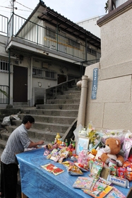 女児の遺体発見現場近くに設置された献花台。奥が君野康弘容疑者宅＝２１日午前、神戸市長田区長田天神町１