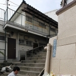女児の遺体発見現場近くに設置された献花台。奥が君野康弘容疑者宅＝２１日午前、神戸市長田区長田天神町１