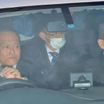 青いフードのようなものをかぶり送検のため車で洲本署を出る平野達彦容疑者（後列左）＝１０日午前１１時８分、洲本市山手２