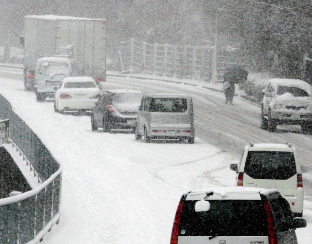路面に積もった雪で走行できなくなり、立ち往生した乗用車＝２０１４年２月、神戸市内